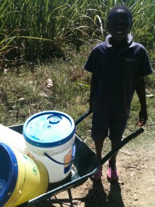 A boy bringing home water from a well for the day. 